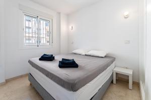 a white room with a bed with two blue pillows on it at Paraiso in Fuengirola
