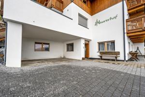 a large white building with a bench in a courtyard at Maurerhof Abendrot in Maranza