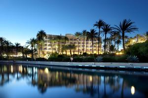 a building with palm trees in front of a body of water at Javea Brisas Del Mar Cofisa in Jávea