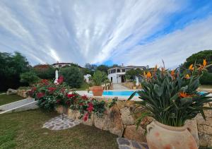 a house with a stone wall with flowers in a yard at Villa Luna Rossa con piscina in San Teodoro