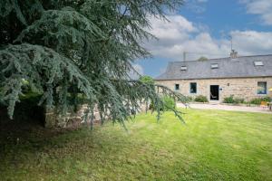 an old stone house with a tree in front of it at Gîte Ty Coz in Lanvellec