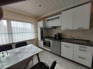 a kitchen with white cabinets and a table and a sink at Ferienwohnung-Pension Osterwiese in Weilburg