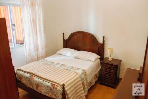 a bedroom with a bed with a wooden headboard and a table at Encanto da Praia in Santo André