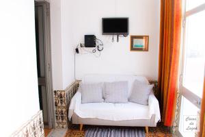 a white couch in a room with a tv at Encanto da Praia in Santo André