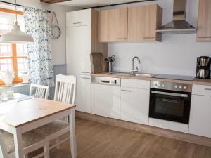 a kitchen with white cabinets and a wooden table at Fachwerktraum im Hof in Alheim