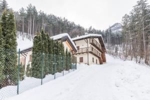 a building in the snow next to a fence at Wellness Lodge Riccardo in Santa Giuliana