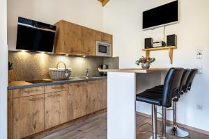 una cucina con mobili in legno e un bancone con sgabelli di Eggerhof Suite a Verano Altre 11 foto