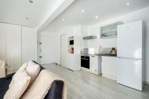 a white living room with a couch and a kitchen at T2 Cyril Besset in Cagnes-sur-Mer