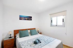 a white bedroom with a large bed with blue pillows at Apartamento La Morena 3a in El Pris