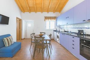 a kitchen with a table and chairs and a blue couch at Casa da Ti Mónica in São Luis