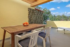 a wooden table and chairs with a bowl of fruit on it at I giardini di Cala D'ambra in San Teodoro