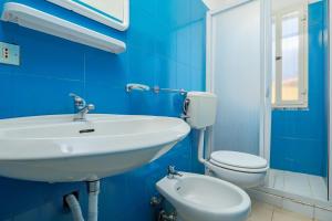 a blue bathroom with a sink and a toilet at I giardini di Cala D'ambra in San Teodoro +12 photos