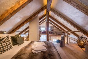 an attic bedroom with a large couch and wooden ceilings at Obereggeralm in Valdaora
