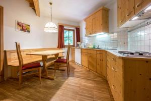 a kitchen with wooden cabinets and a table with chairs at Lindenhof Apt 4 in Vandoies