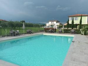 a large blue swimming pool with chairs and a house at Villa Manuela Flat in Chiesina Uzzanese