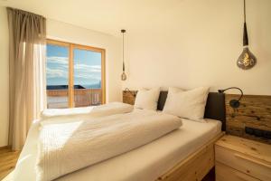 a bedroom with a large white bed with a window at Apt Lärche - Nockerhof in Andrian