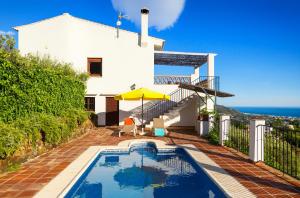 a pool in front of a house with a view of the ocean at Villa El Regalo in Frigiliana