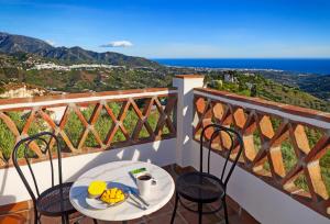 a table and chairs on a balcony with a view of the ocean at Villa El Regalo in Frigiliana
