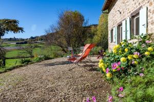 a red chair sitting outside of a house with flowers at Le Mas Saint Victor in Saint-Victor