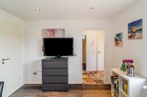 a living room with a television on a dresser at Krummes Häusschen an der Nordsee in Großheide