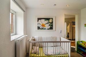 a baby crib in a room with a painting of a flower at Krummes Häusschen an der Nordsee in Großheide