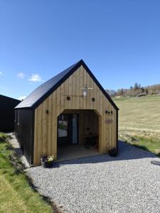 a large wooden barn with a door in a field at Temuka Lodge in Glenurguhart