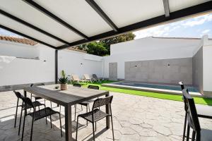 an outdoor patio with a wooden table and chairs at Alce piscina climatizada in Chiclana de la Frontera