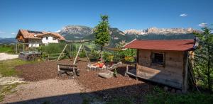 a backyard with a playground with a swing and a house at Furnerhof Apt Olpenglühn in Collepietra