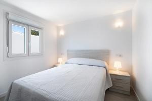 a white bedroom with a bed and two lamps at Alce piscina climatizada in Chiclana de la Frontera +22 photos