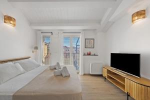 a white bedroom with a large bed and a flat screen tv at Cinema Boutique Apartment Sestri in Sestri Levante