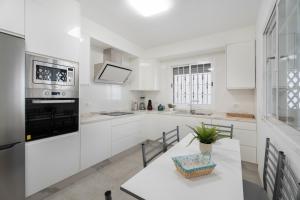 a kitchen with white cabinets and a table with a plant at Villa en Las Caletillas in Punta Larga