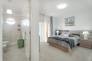 a white bedroom with a bed and a bathroom at Villa en Las Caletillas in Punta Larga