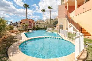 a swimming pool in front of a building with palm trees at El Mirador in Mutxamel