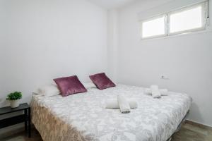 a white bedroom with a large bed with purple pillows at El Mirador in Mutxamel +17 photos