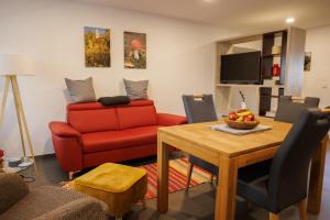 a living room with a red couch and a table at Ferienwohnung Alter Kuhstall in Neuenstein