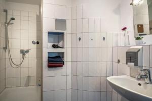 a white tiled bathroom with a shower and a sink at Ferienwohnung Schläfer in Kappel-Grafenhausen +13 photos