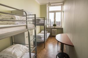 a dorm room with bunk beds and a table and a window at Bubble Hostel in Krakow