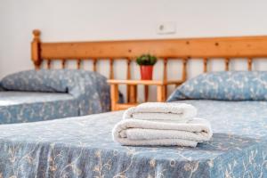 three towels are stacked on a blue bed at Apartamentos Karin 1ºb in Santanyi +20 photos