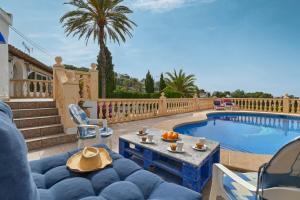 a patio with a blue couch and a swimming pool at Dulce in Benissa