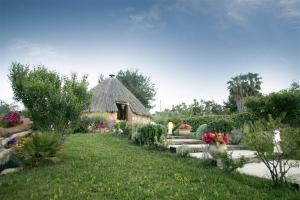 a garden with a thatched building with flowers and plants at Pinnetta Sarda in Codrongianos