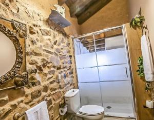 a bathroom with a toilet and a stone wall at Jumaca in Valdespino de Somoza