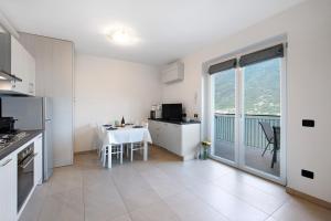 a white kitchen with a table and a balcony at Appartamento 3 Il Tornante in Nesso