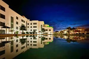 a building with its reflection in the water at night at Beach Apartment with Pool, Terrace in Taramay
