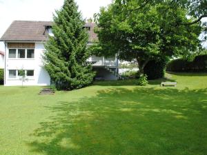 a white house with a tree and a grass yard at Ferienhaus Joos in Uhldingen-Mühlhofen