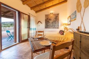 a bedroom with a bed and a dining table and a table at Stazzo Jana in Trinità d'Agultu e Vignola