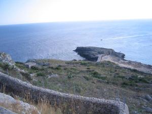 a stone wall on a hill near the ocean at Lu Rusciu De Lu Vientu in Castrignano del Capo