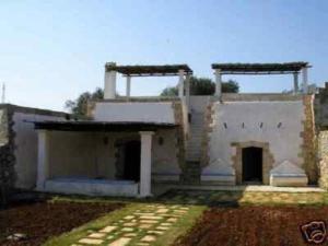 a white building with two doors and a yard at Lu Rusciu De Lu Vientu in Castrignano del Capo
