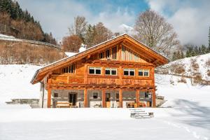a large wooden cabin in the snow with snow covered at Maroc Mountain Chalet in Madonna di Campiglio
