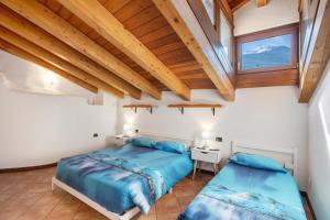 two beds in a bedroom with wooden ceilings at Appartamento nel borgo di Chatillon in Châtillon