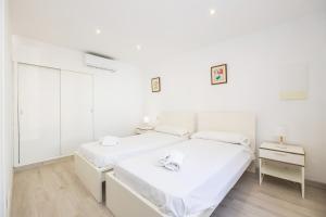 two beds in a room with white walls and wooden floors at Ca Na Bel in Cala Ratjada